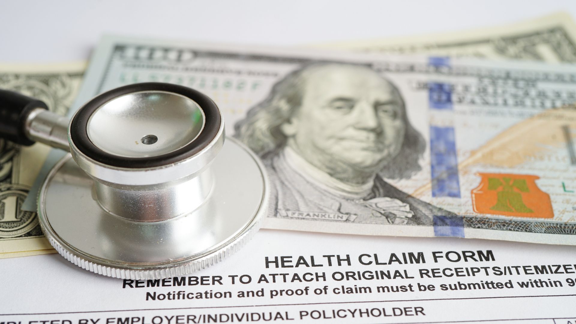 Health claim form with stethoscope and US dollar banknotes insurance accident medical concept