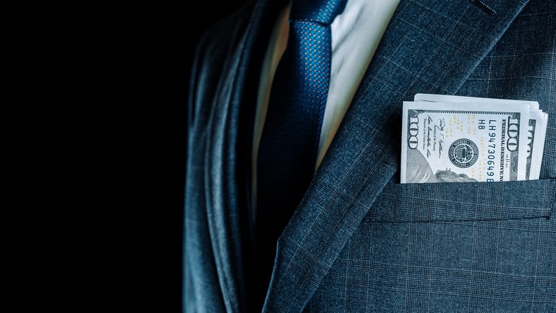 A person in a suit with cash in their chest pocket